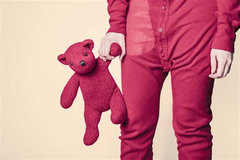 Child in red pajamas holding red teddy bear