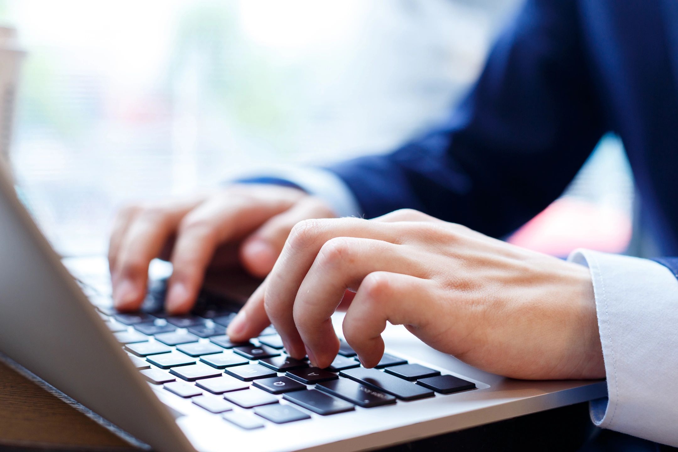 Person sits at a desk and types on a laptop