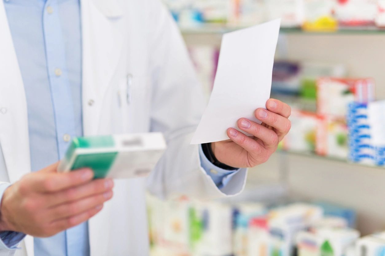 Doctor holding a box of pills and a prescription