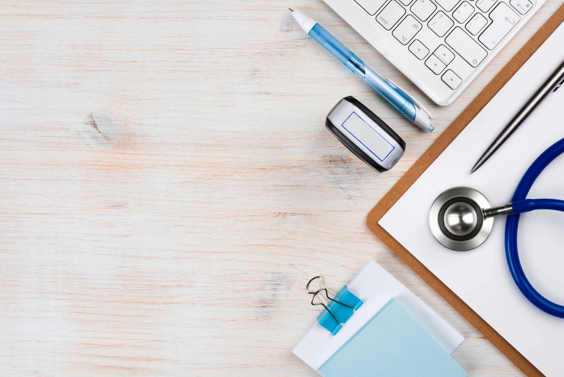 desk with keyboard, pen, notepad and stethoscope