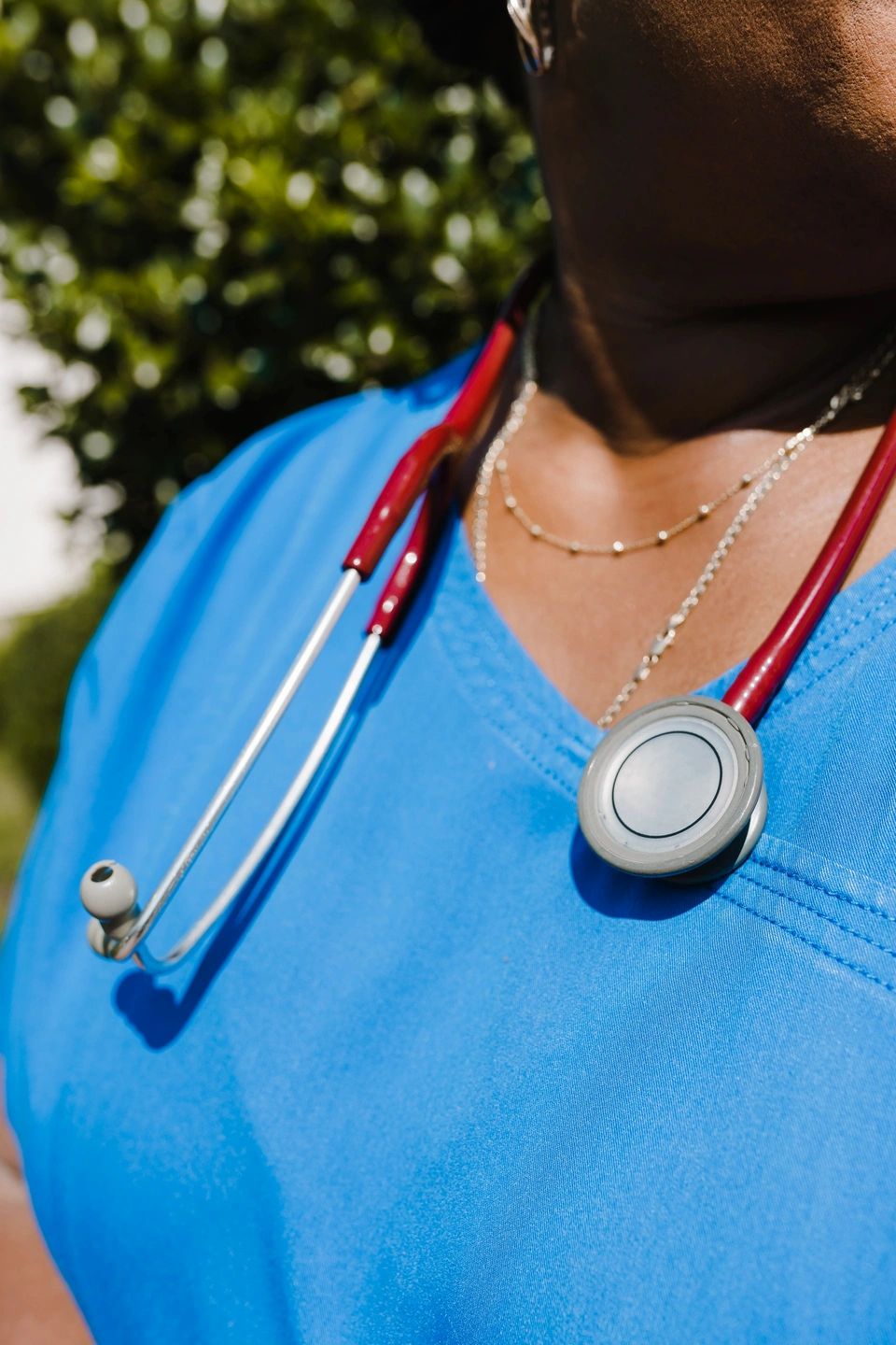 Woman in blue scrubs with red stethoscope around her neck