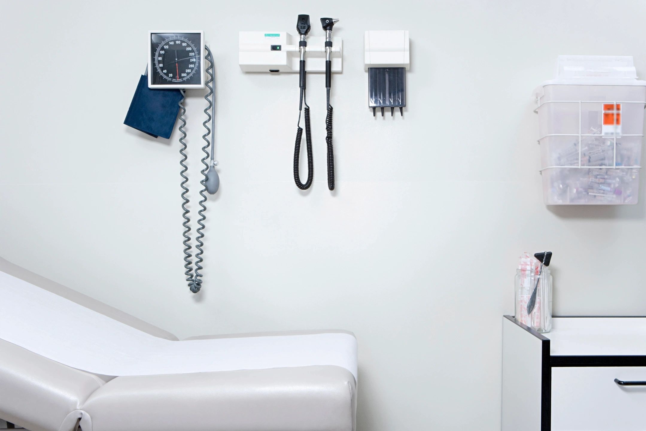 Medical exam room, with table, BP cuff, and lighted magnifying equipment