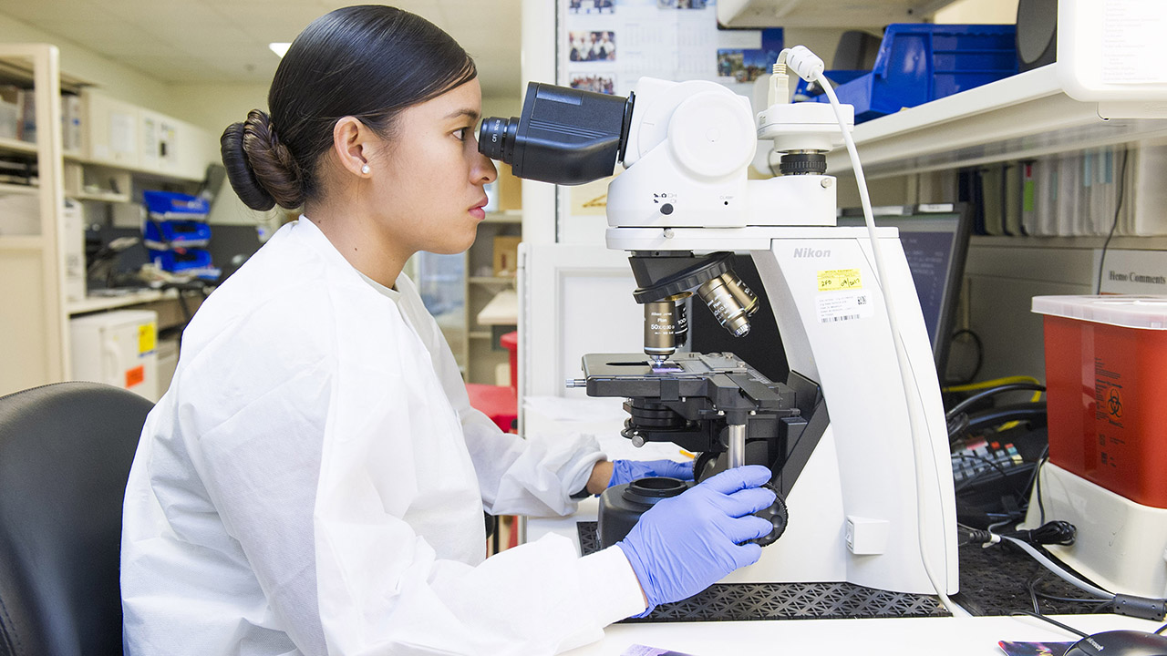 Laboratory technician looking through microscope